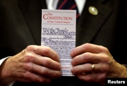 FILE - A member of Congress holds a copy of the U.S. Constitution during a press conference in the U.S. Capitol in Washington June 20, 2017. While the Constitution lays out conditions under which a president can be impeached and removed from office, it does not directly address whether the president can be prosecuted.