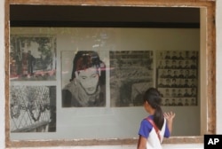 FILE - A Cambodian girl looks at images of Khmer Rouge victims displaying at Tuol Sleng genocide museum, formerly the regime's notorious S-21 prison in Phnom Penh, Cambodia, March 26, 2015.