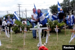 FILE - Demonstrators stand next to crosses at a memorial for victims killed in recent protests against Nicaraguan President Daniel Ortega's government, during a protest in Managua, Nicaragua, Aug. 4, 2018.