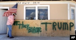 John Murray attaches a U.S. flag to a sign reading "Bet They Blame Trump" at his business damaged in the wake of Hurricane Harvey, Aug. 29, 2017, in Rockport, Texas.