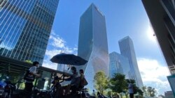 Residents pass near the headquarters for Evergrande in Shenzhen in southern China, Sept. 23, 2021.