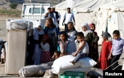FILE - A boy sits on wheat flour as others stand by aid they received from a Saudi distribution center at a camp for internally displaced people (IDPs) near Marib, Yemen, Jan. 26, 2018.