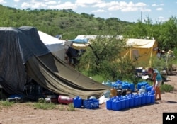 FILE - No More Deaths volunteer Katie Maloney checks water jugs at the group's camp, near Arivaca, Ariz., about 13 miles north of Mexico, before heading out to supply water stations for migrants illegally crossing the border.