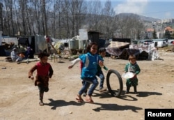 Syrian refugee children run in a tented settlement, in the town of Qab Elias, in Lebanon's Bekaa Valley, March 13, 2018.