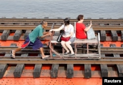 A man pushes a trolley that transports commuters along a railroad track in Manila, Philippines February 21, 2017.