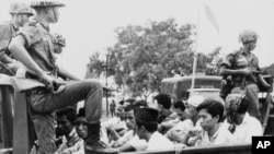 Members of the Youth Wing of the Indonesian Communist Party are guarded by soldiers as they are taken by an open truck to prison in Jakarta following a crackdown on communists in 1965.
