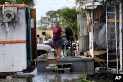 Elida Dimas looks at floodwaters from her porch, in the aftermath of Hurricane Irma, in Immokalee, Florida, Sept. 11, 2017.