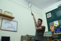 In this March 19, 2020, photo, a PE teacher demonstrates a badminton technique to his students during an online class at Nguyen Tat Thanh school in Hanoi, Vietnam. (AP Photo/Hau Dinh)