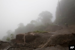 Neighbors walk in the rain from Tropical Storm Nate that helped wash out a road in Alajuelita, Costa Rica, Oct. 5, 2017.