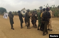 Boko Haram militants (in camouflage) embrace and shake hands with Boko Haram prisoners, released in exchange for a group of 82 Chibok girls, who were held captive for three years by the Islamist militant group, near Kumshe, Nigeria, May 6, 2017.