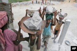 FILE - Child laborers carry stones on their head at a stone crusher on the outskirts of Gauhati, India, June 11, 2008.