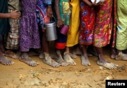Bare feet of Rohingya refugee children are pictured as they stand in a queue while waiting to receive food outside the distribution center in Palongkhali makeshift refugee camp in Cox's Bazar, Bangladesh, Nov. 7, 2017.