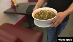 Pho is served in a large white bowl, with light rice noodles, beef -- which has been cooled so it can be sliced very thin -- and vegetables.
