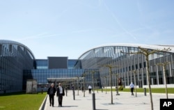 People walk outside the entrance of the new NATO headquarters in Brussels on April 19, 2018. NATO ministers will hold their last meeting in the old headquarters on April 27, 2018 before moving permanently to a new building across the street.