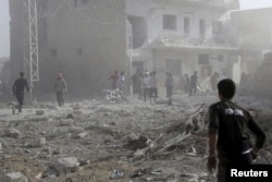 FILE - Residents inspect a site damaged by what activists said was a barrel bomb dropped by forces loyal to Syria's president Bashar Al-Assad in Maarat Al-Nouman, south of Idlib, June 8, 2015.