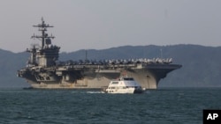 A Vietnamese passenger boat sails past U.S aircraft carrier USS Carl Vinson as it docks in Danang bay, Vietnam on Monday, March 5, 2018. (AP Photo/ Hau Dinh)
