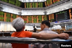 People look at trading boards at a private stock market gallery in Kuala Lumpur, Malaysia, May 14, 2018.