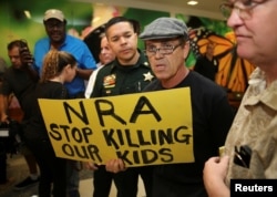 A man with a sign is seen after the news conference in the hallway outside the courtroom where Nikolas Cruz appeared via video at a bond court hearing after being charged with 17 counts of premeditated murder, in Fort Lauderdale, Florida, U.S., Feb.15, 20