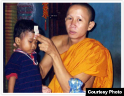 FILE - A Buddhist monk blesses 2-year-old Jordan Pisey Windle before he left his homeland to join his father, Jerry Windle, in Florida, United States.