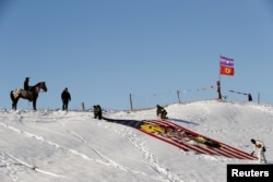 A young Native American man on horseback watches veterans unfurl a flag near the Oceti Sakowin camp as "water protectors" continue to demonstrate against plans to pass the Dakota Access pipeline near the Standing Rock Sioux Reservation, near Cannon Ball, N.D., Dec. 4, 2016.