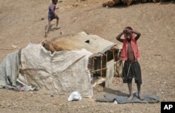 FILE - A young boy stands outside his small shelter in the United Nations protection of civilians site in Bentiu, South Sudan, Dec. 9, 2018.