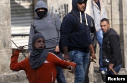 A Palestinian boy uses a sling to hurl stones towards Israeli troops during clashes in the West Bank city of Hebron, Oct. 29, 2015.