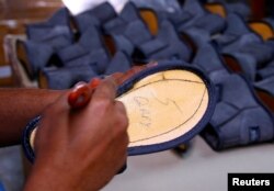A worker applies glue at a factory making sheep-skin boots called 'Ugg boots' in western Sydney, Australia, Oct. 26, 2016 as they produce products for numerous orders for customers in China.