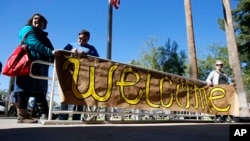 FILE - Supporters place a sign welcoming Syrian refugees is placed at the entrance to the office of the Arizona governor during a rally at the Arizona Capitol in Phoenix, Nov. 17, 2015.