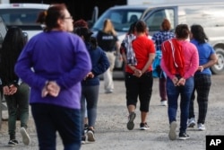 Government agents lead suspects in custody toward a restroom during an immigration sting at Corso's Flower and Garden Center in Castalia, Ohio, June 5, 2018.