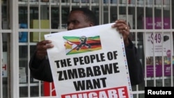 A man carries a poster calling for Zimbabwe President Robert Mugabe to step down as Zimbabweans take to the streets in Harare, Zimbabwe, Nov. 18, 2017.