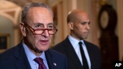 Senate Minority Leader Chuck Schumer, D-N.Y., with Sen. Cory Booker, D-N.J., at right, pauses as they speak to reporters about the political battle for confirmation of President Donald Trump's Supreme Court nominee.