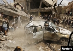 File - A car falls as it is being lifted by a crane at the site of a Saudi-led air strike in Yemen's capital Sana'a Sept. 21, 2015.