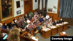 Lowell residents attended the city council session with signs “Lowell High School Downtown” in early June, as the council debated on whether to renovate or move Lowell High School. (Courtesy photo of Common Wealth Magazine)