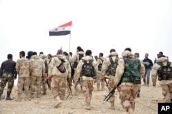 In this photo released by the Syrian official news agency SANA, Syrian soldiers gather around a Syrian national flag in Palmyra, Syria, March 27, 2016.