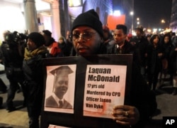 FILE - A protester holds a sign as people rally in memory of 17-year-old Laquan McDonald, who was shot 16 times by Chicago Police Department Officer Jason Van Dyke, in Chicago, Nov. 24, 2015.