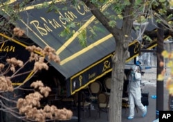 FILE - An investigator works outside the Bataclan concert hall in Paris, Nov. 14, 2015.