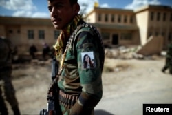Yazidi Popular Mobilisation Forces fighter Hussein Eisso hangs a photo of Nadia Murad, a Yazidi survivor and U.N. Goodwill Ambassador, on his arm in Kojo, Iraq June 1, 2017.