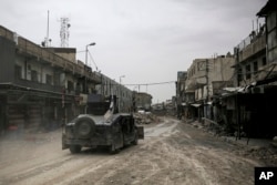 FILE - A humvee of the Iraqi Federal Police drives through an abandoned street in western Mosul, Iraq, May 2, 2017.