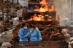Kerabat pasien COVID-19 yang meninggal di sebuah krematorium di Desa Giddenahalli di pinggiran Bengaluru, India, 13 Mei 2021. (Foto: Samuel Rajkumar/Reuters)