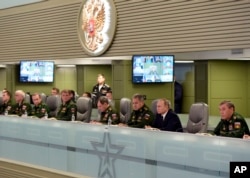 Russian President Vladimir Putin, second right, flanked by Defense Minister Sergei Shoigu, third right, and Chief of the General Staff of the Russian Armed Forces Valery Gerasimov, right, attends a meeting on Russian airspace forces' activities in Syria.