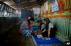 Rahima Akter, left, teaches her siblings inside the family hut in Kutupalong refugee camp.