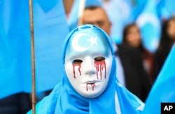 In Brussels on April 27, 2018, a person wearing a white mask with tears of blood takes part in a protest march of ethnic Uighurs asking for the European Union to call upon China to respect human rights in the Chinese Xinjiang region.
