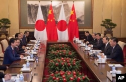 Japanese Prime Minister Shinzo Abe, left, talks with Chinese President Xi Jinping, right, during a meeting at the Diaoyutai State Guesthouse in Beijing, China, Oct. 26, 2018.