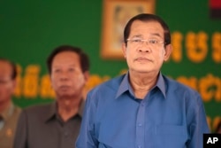 Cambodia's Prime Minister Hun Sen, right, prepares to deliver a speech during a factory visit outside of Phnom Penh, Cambodia, Aug. 30, 2017.