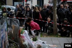 A small girl lays flowers as part of a memorial to victims a day after more than 120 people were killed in a series of attacks in Paris, Nov. 14, 2015.