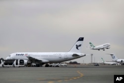 FILE - An Iranian Mahan Air passenger plane takes off as a plane of Iran's national air carrier, Iran Air, is parked at left, at Mehrabad airport in Tehran, Feb. 7, 2016.