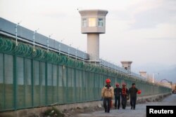 Workers walk by the perimeter fence of what is officially known as a vocational skills education centre in Dabancheng in Xinjiang Uighur Autonomous Region, China September 4, 2018.