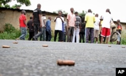A man looks across at spent bullet casings lying on a street in the Nyakabiga neighborhood of Bujumbura, Burundi, Saturday, Dec. 12, 2015.