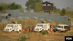 Internally displaced people walk next to U.N. vehicles on the perimeter of a protection of civilians (POC) site in Juba, South Sudan, Dec. 5, 2016. (J. Craig/VOA)