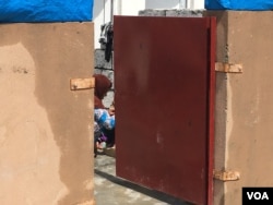 Iraqi woman who fled IS controlled village seen through the gate of a housing unit in a Kurdish-run camp for families fleeing IS control, outside Makhmour, Iraq, April 11, 2016. (S. Behn/VOA)